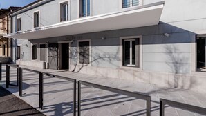 Un edificio moderno con fachada plana, amplios ventanales y un corredor cubierto.