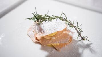 A dessert with powdered sugar and a sprig of rosemary on a white plate.