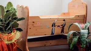 Una cama de madera con cabecera, un cuadro en la pared y plantas en macetas.