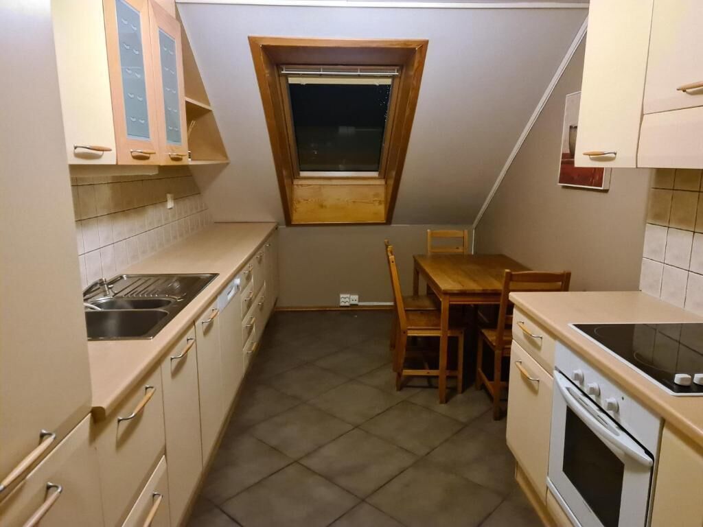 Une cuisine de taille réduite, dotée d’une fenêtre, d’un évier, d’une cuisinière et d’une table à manger.