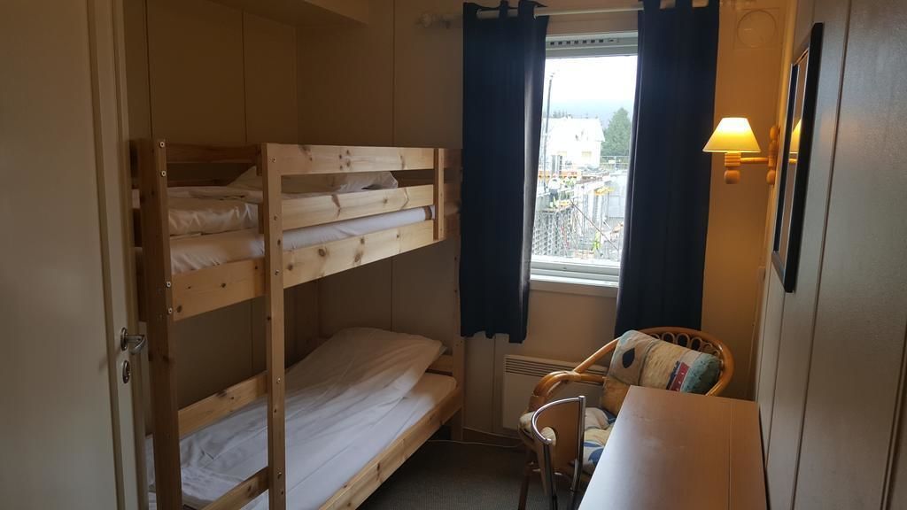 Dormitorio con literas, ventana, silla y mesa.