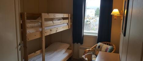 Dormitorio con literas, ventana, silla y mesa.