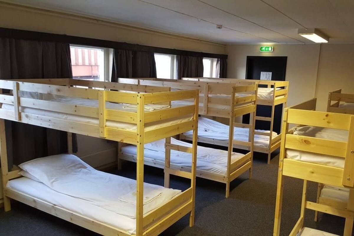 Un dormitorio con literas, una ventana con cortinas y un letrero de salida de emergencia.