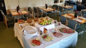 Montaje tipo bufé con diversos alimentos y una mesa con mantel blanco.