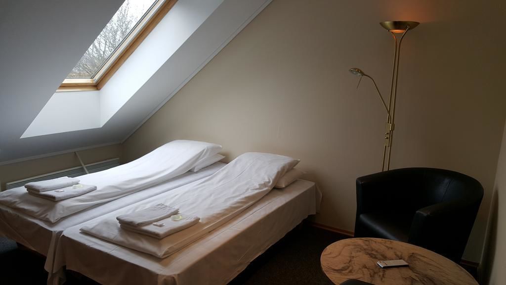 A small, simple room with a single bed, a chair, and a small table.