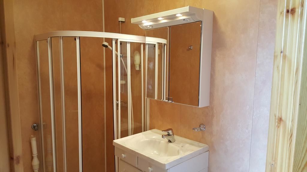 Un baño con un lavamanos blanco, un espejo y una cabina de ducha.