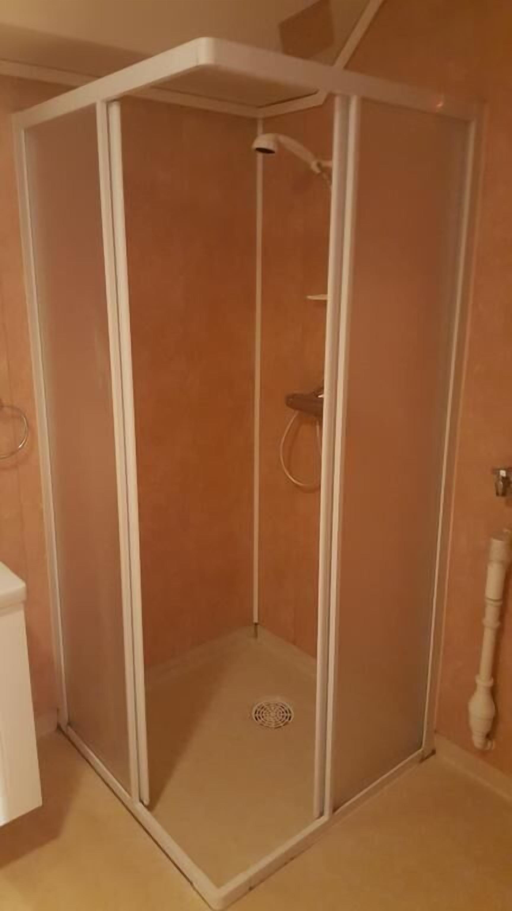Ducha a pie con puerta de cristal y cabezal.