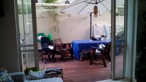 An outdoor patio area with a table and chairs, a blue tablecloth, and a wind chime. - Wonderful Room Garden Apartment (Tel Aviv)