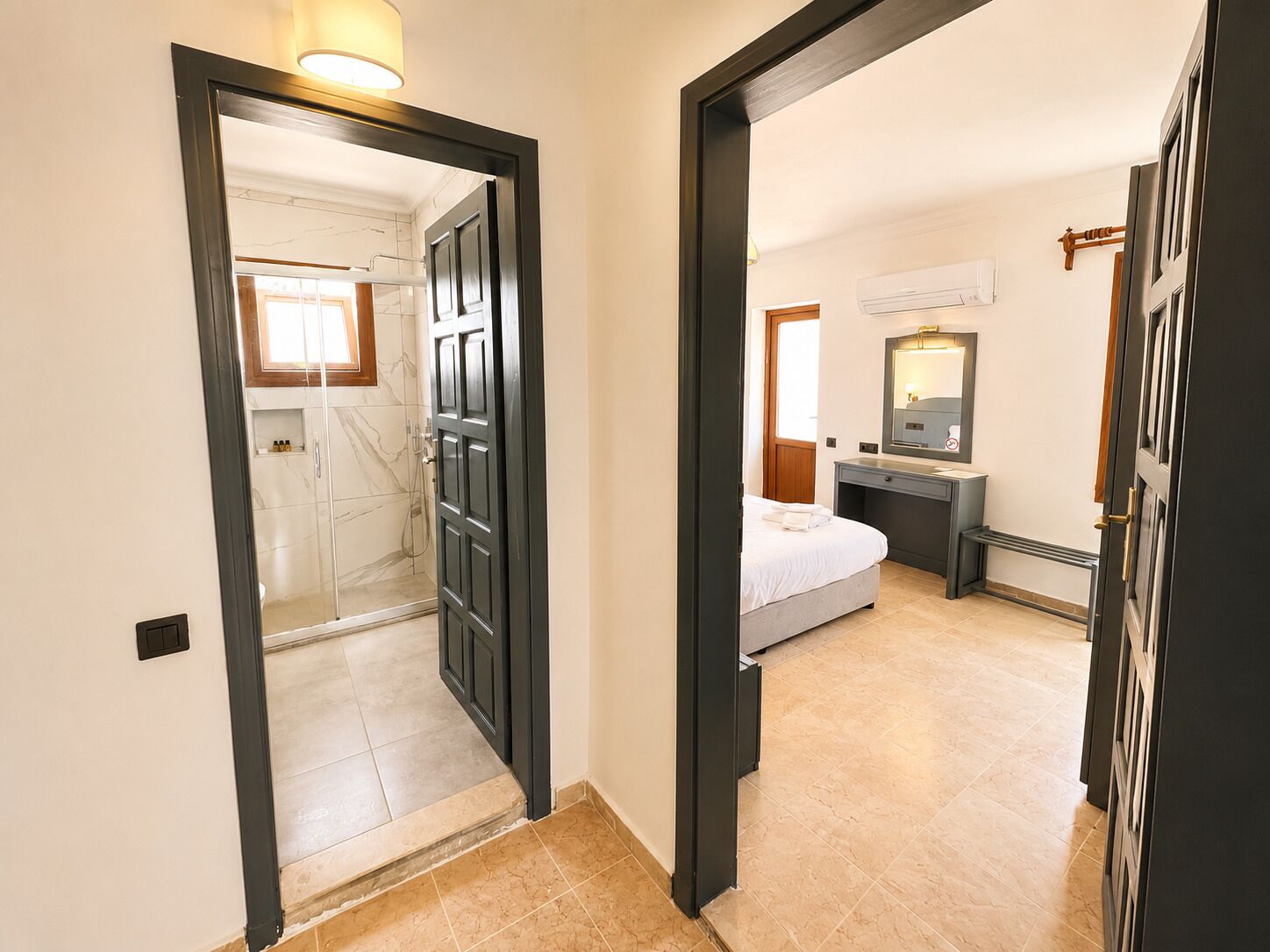 Ein Hotelzimmer mit Dusche, einem Bett, einem Schreibtisch und einem Spiegel.