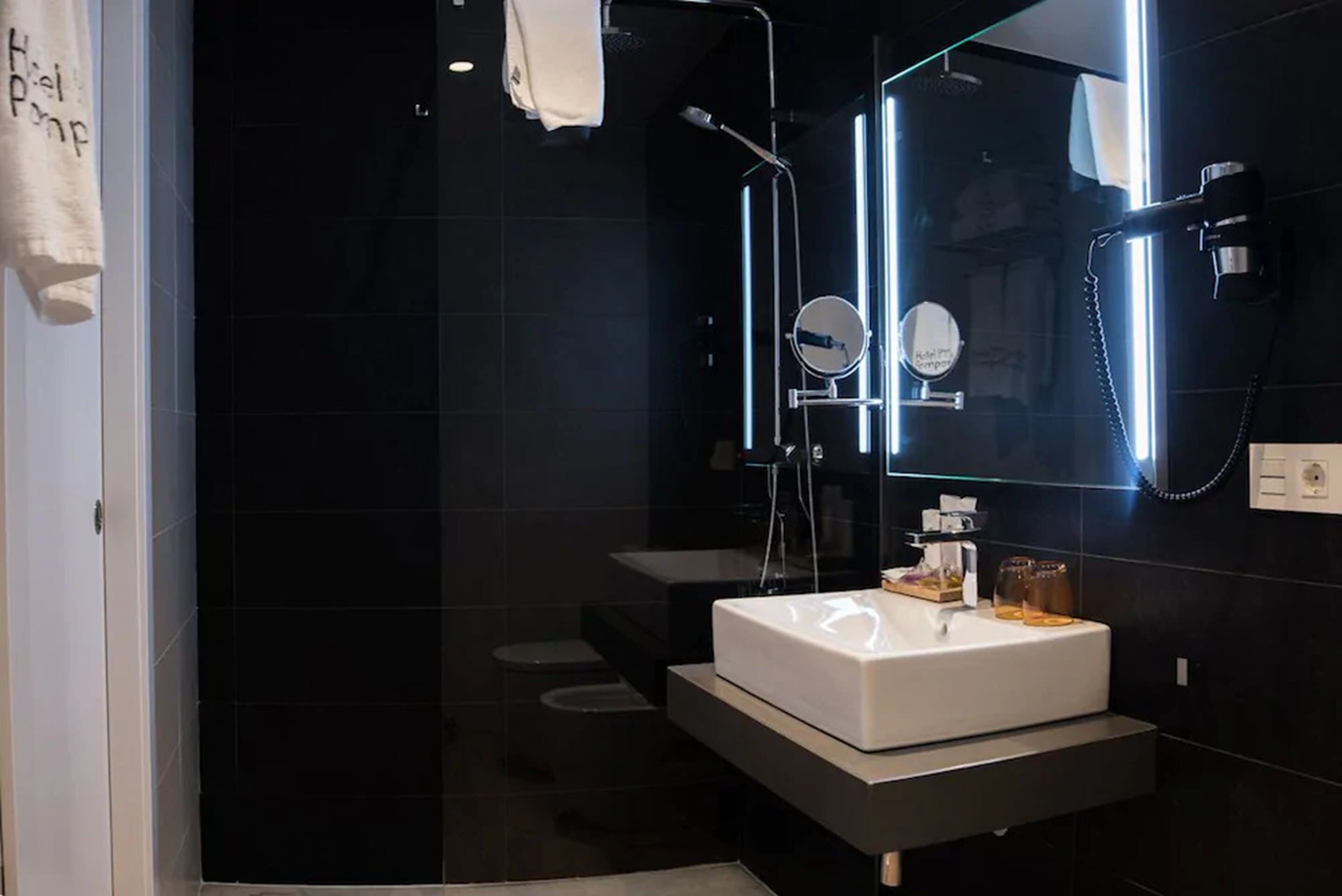 A modern bathroom with a white sink, a mirror, and a shower area.
