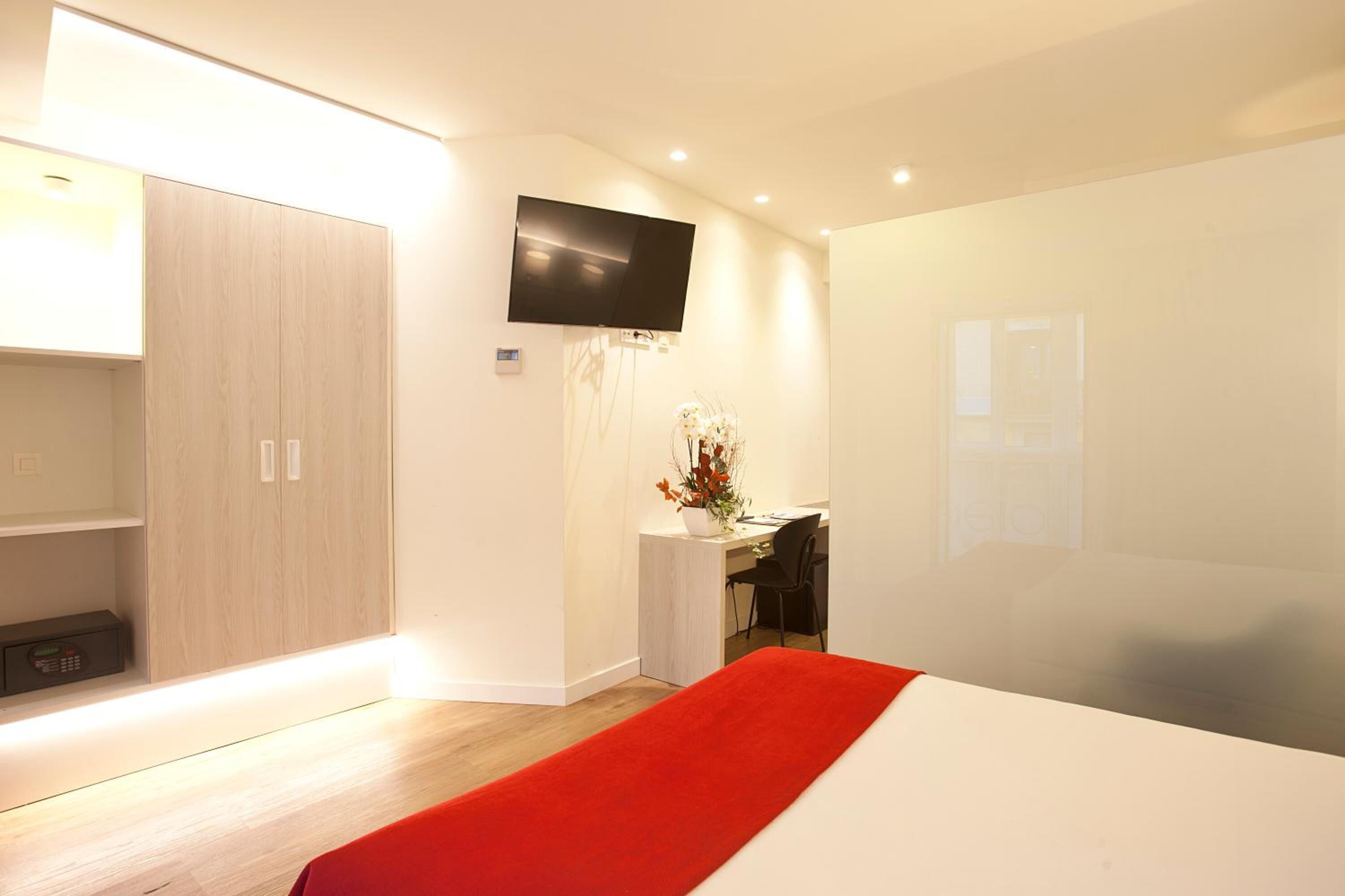 Una habitación de hotel moderna con una cama grande, un escritorio, un televisor y un armario.