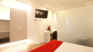 Una habitación de hotel moderna con una cama grande, un escritorio, un televisor y un armario.