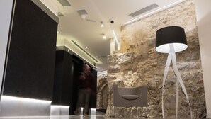 Un hall d’entrée moderne avec un mur en pierre, un fauteuil contemporain et un lampadaire.