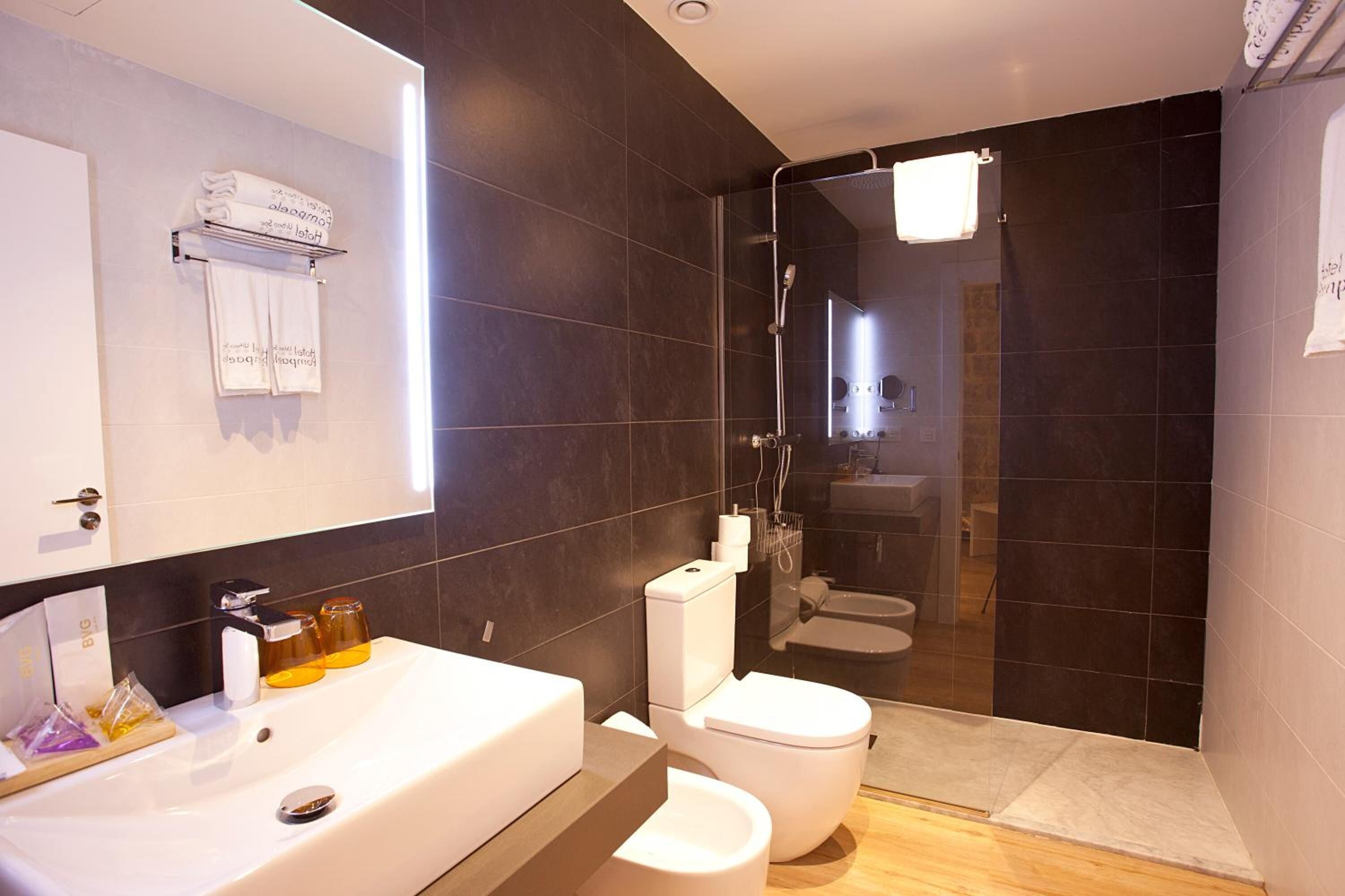 Een moderne badkamer met een badkuip, toilet en douchecabine met glazen wanden.
