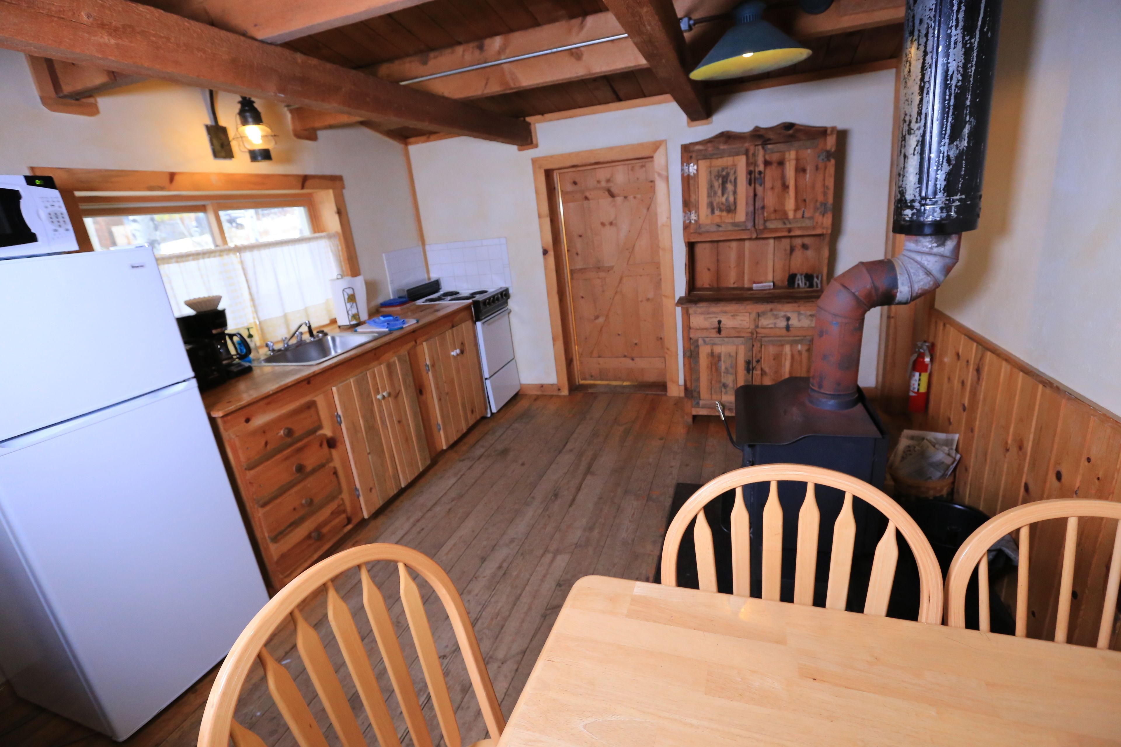A rustic kitchen with wooden cabinets, a stove, and a dining table with chairs.