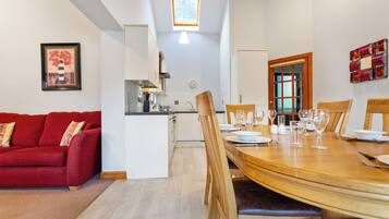 Une cuisine moderne avec des meubles blancs, un canapé rouge et une table à manger dressée pour six personnes.