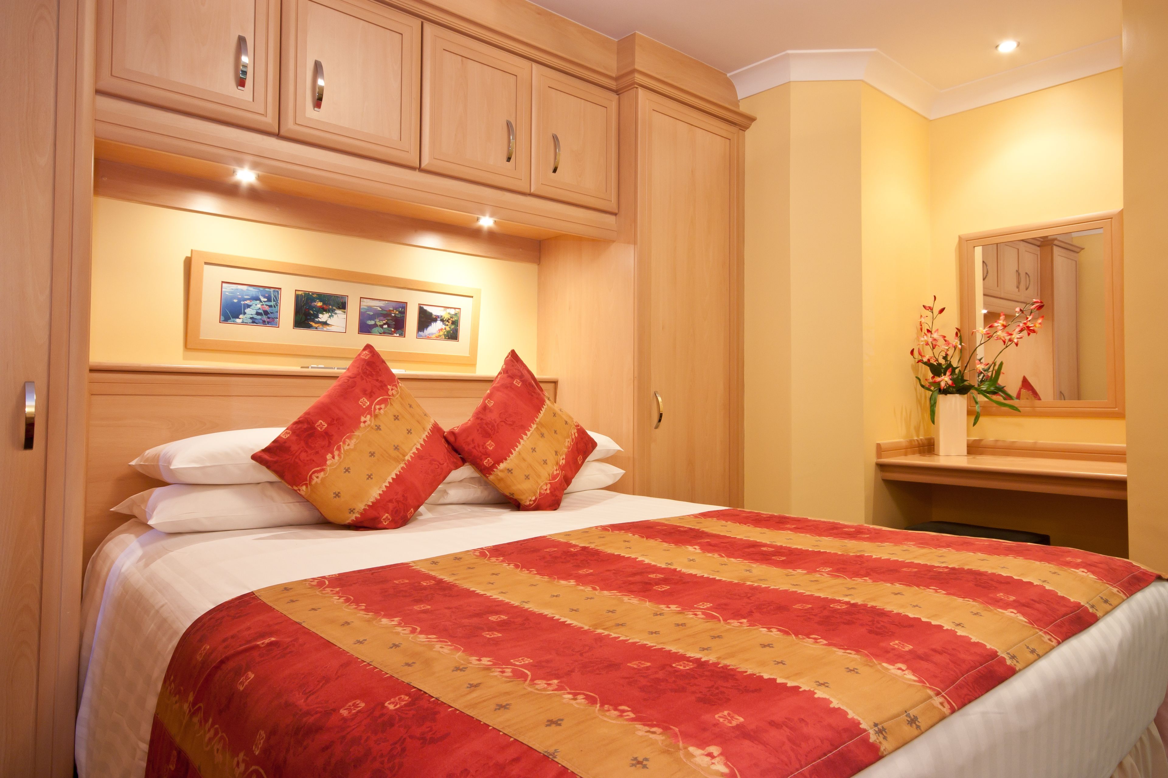 Una habitación de hotel con una cama grande, cabecero de madera y un espejo sobre la cama.