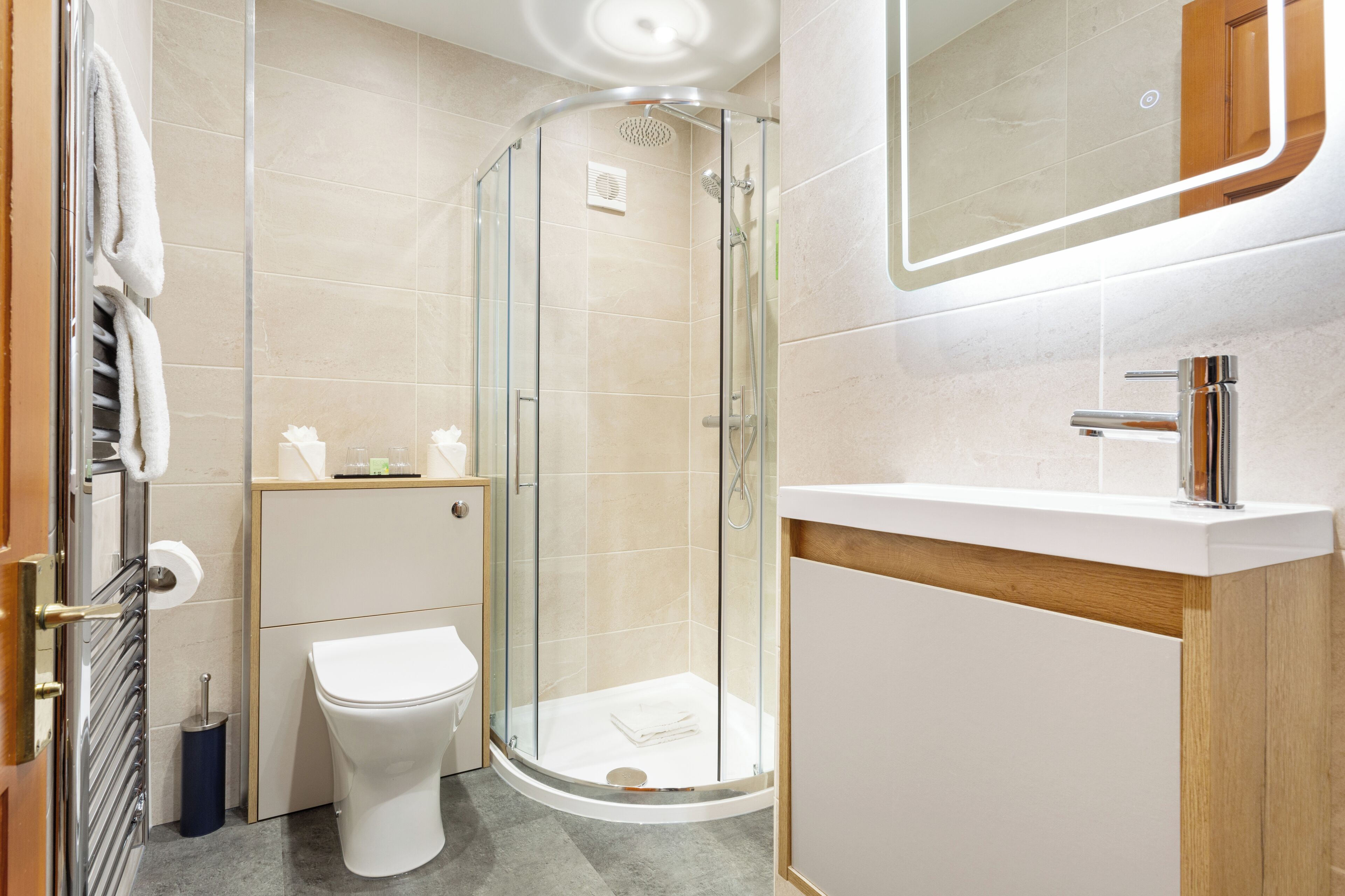 Ein modernes Badezimmer mit einer Duschkabine, einer weißen Toilette und einem Holzwaschtisch.