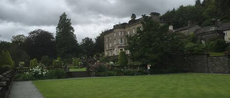 A large, historic building with a formal garden in front.