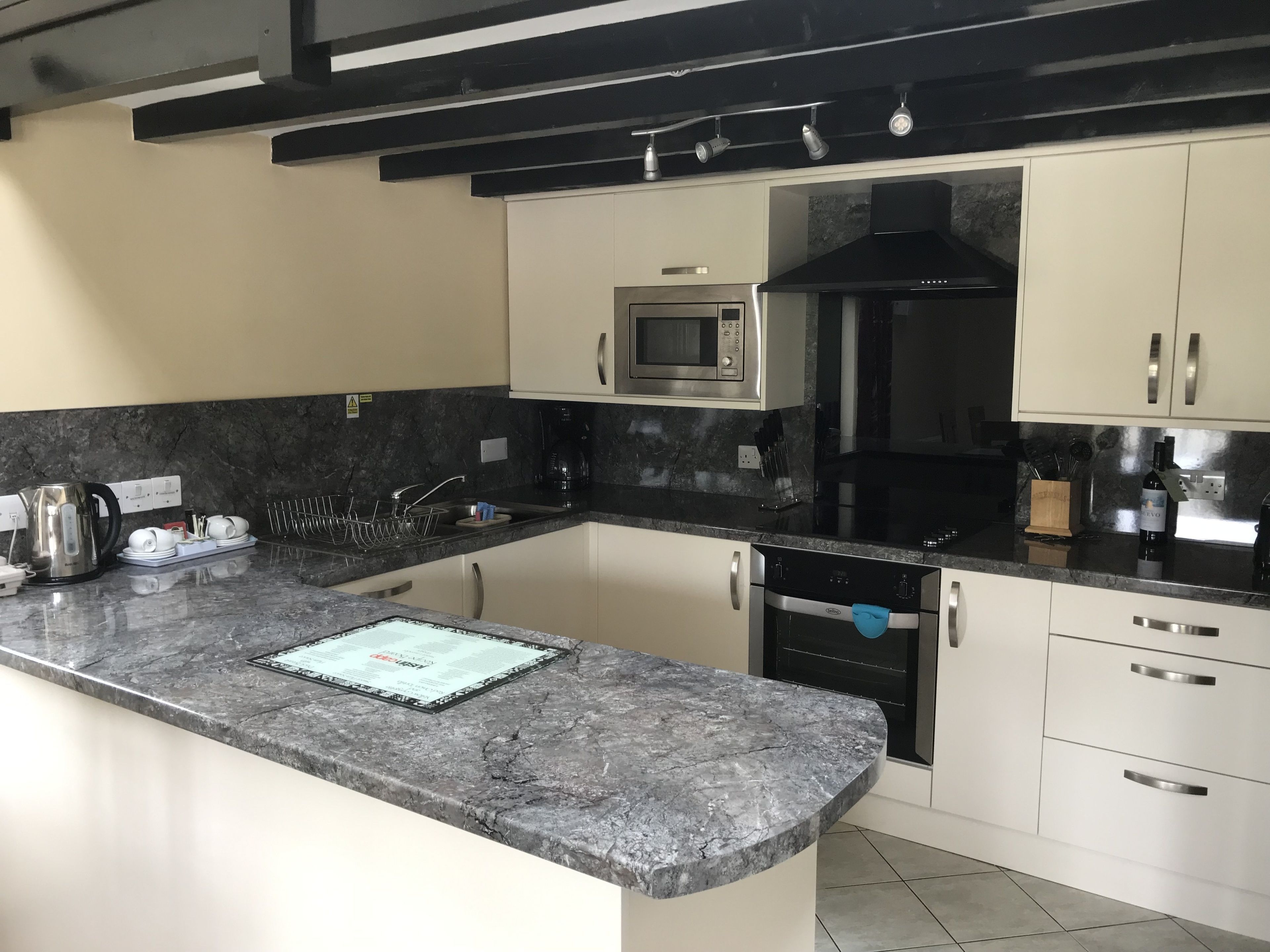 A modern kitchen with a granite countertop, stainless steel appliances, and white cabinetry.