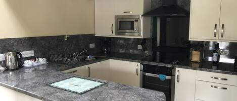 A modern kitchen with a granite countertop, stainless steel appliances, and white cabinetry.