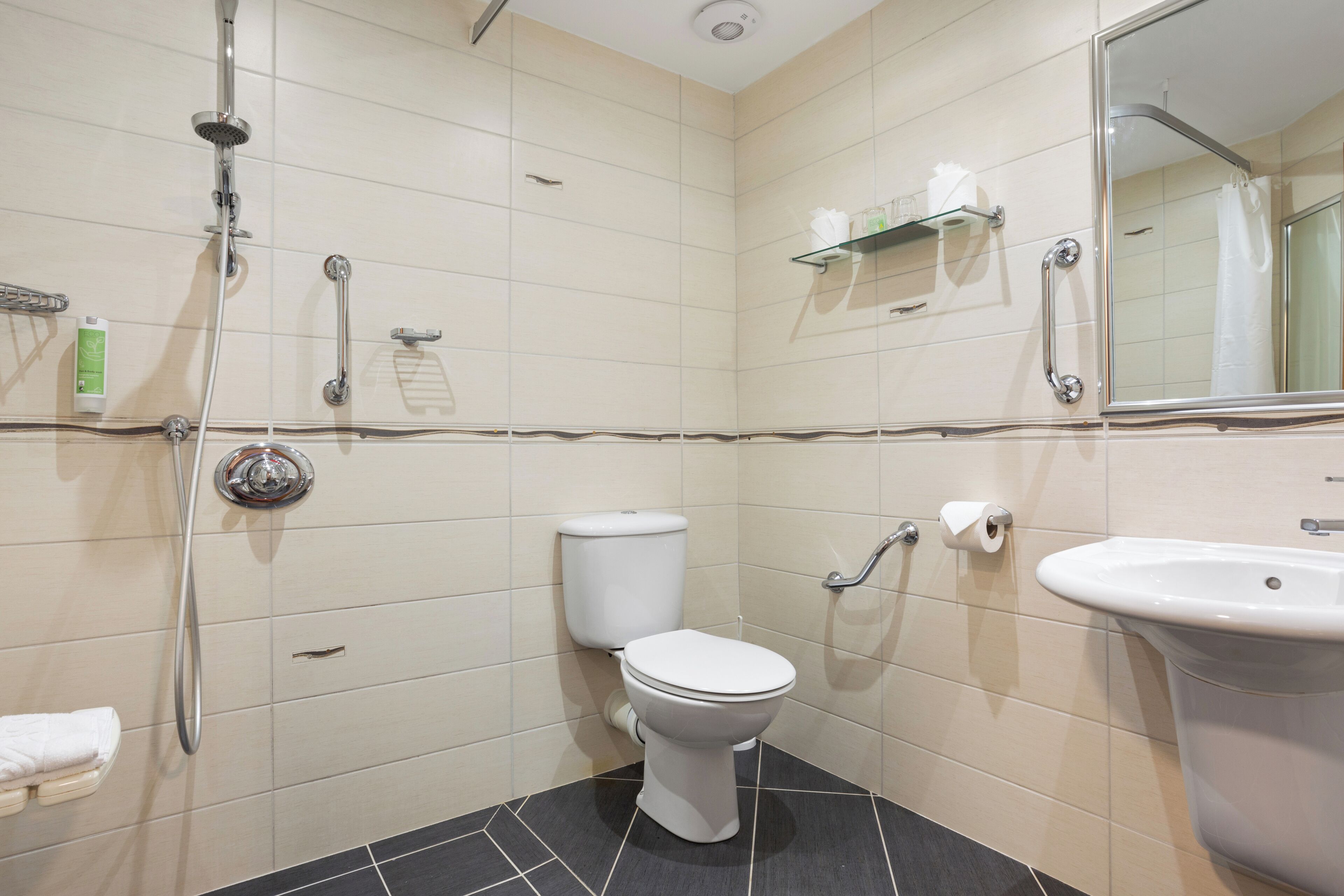 A modern bathroom with a toilet, sink, shower, and a mirror.