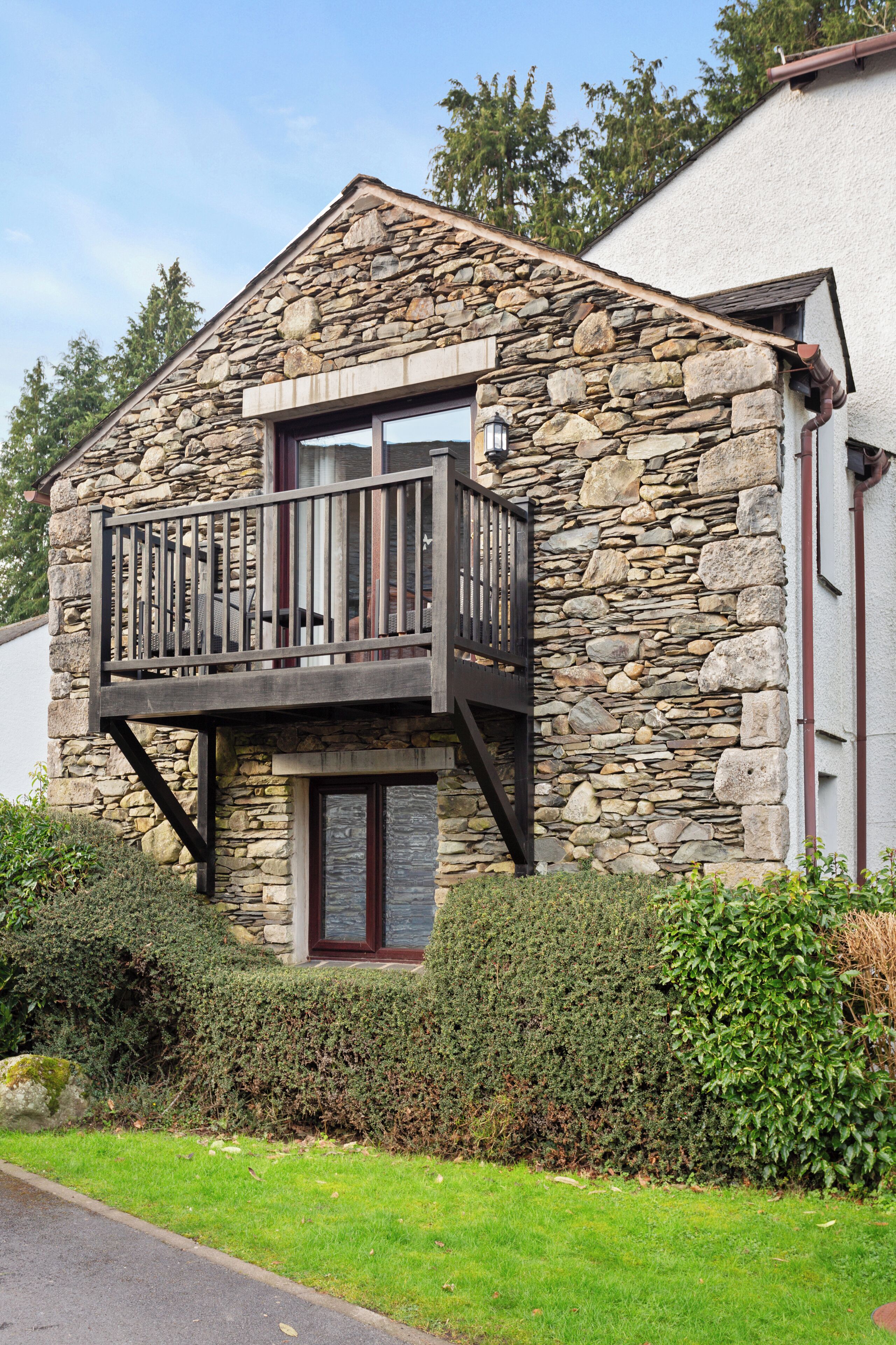 A stone building with a balcony, a door, and a window.