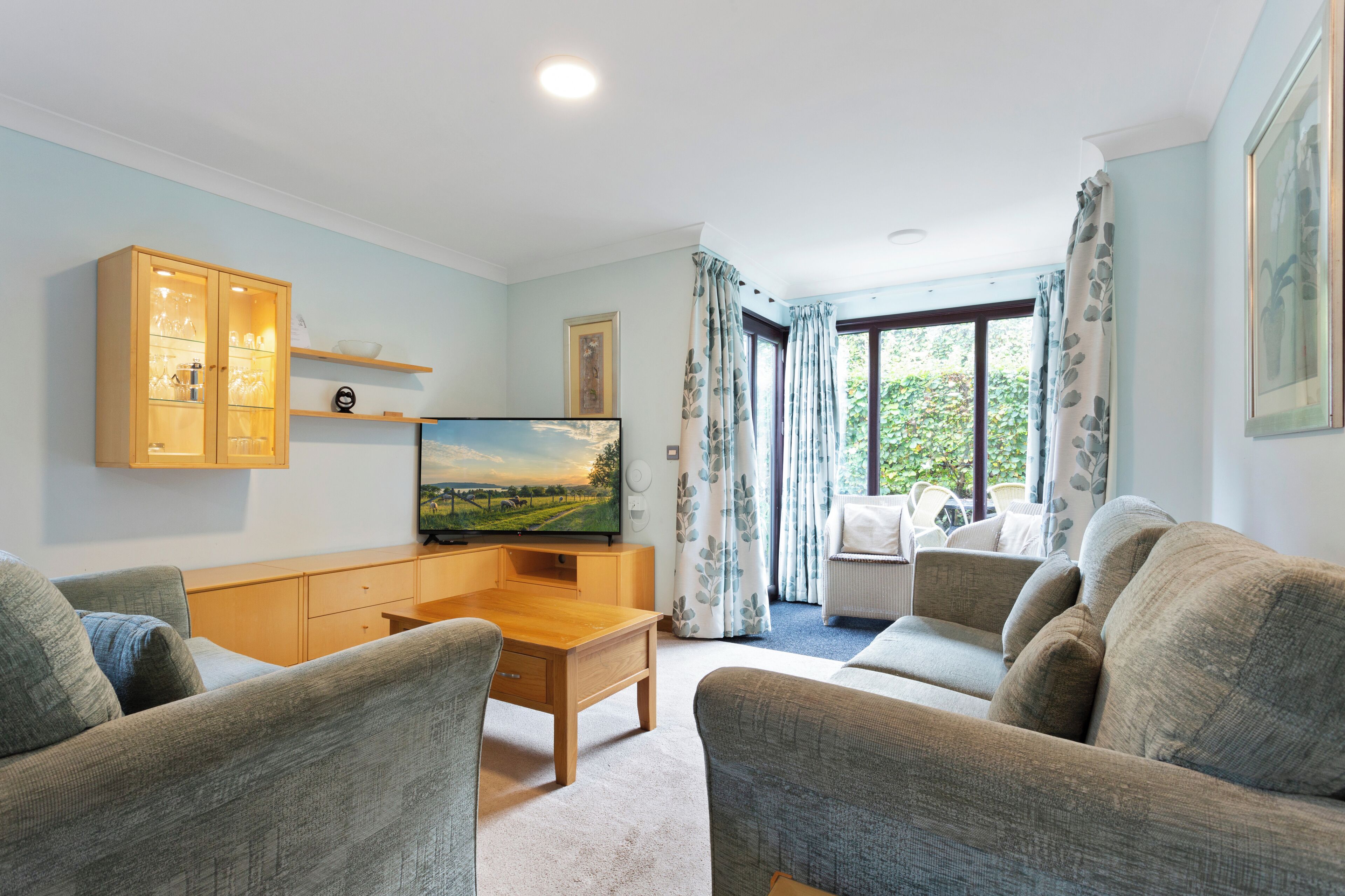 A living room with a wooden cabinet, a television, and two sofas.