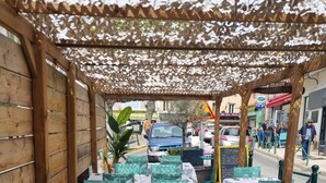 An outdoor dining area with tables and chairs, covered by a wooden structure with a patterned canopy. - Logis Hôtel La Clé des Songes (Pierrefeu-du-Var)