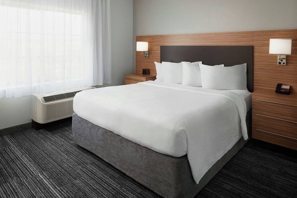 Een hotelkamer met een groot bed, een nachtkastje, een lamp en een verwarming.