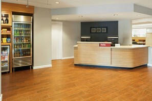 A reception area with a wooden reception desk, a refrigerator stocked with beverages, and a counter with a 'hello' sign.