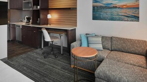 A modern kitchenette with a microwave, coffee maker, and a dining area with a chair and table.