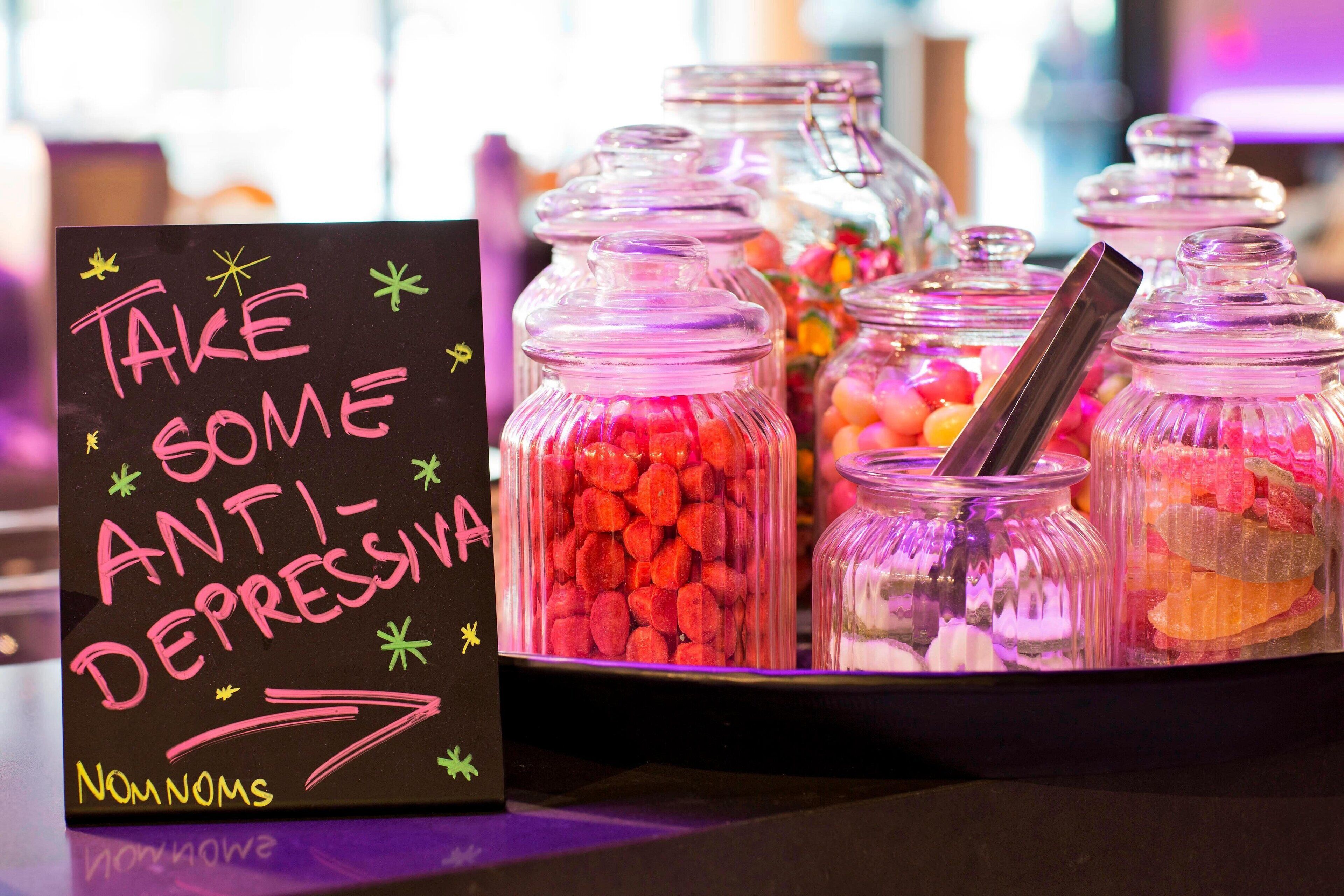 A sign with colorful text and a tray of assorted candies.