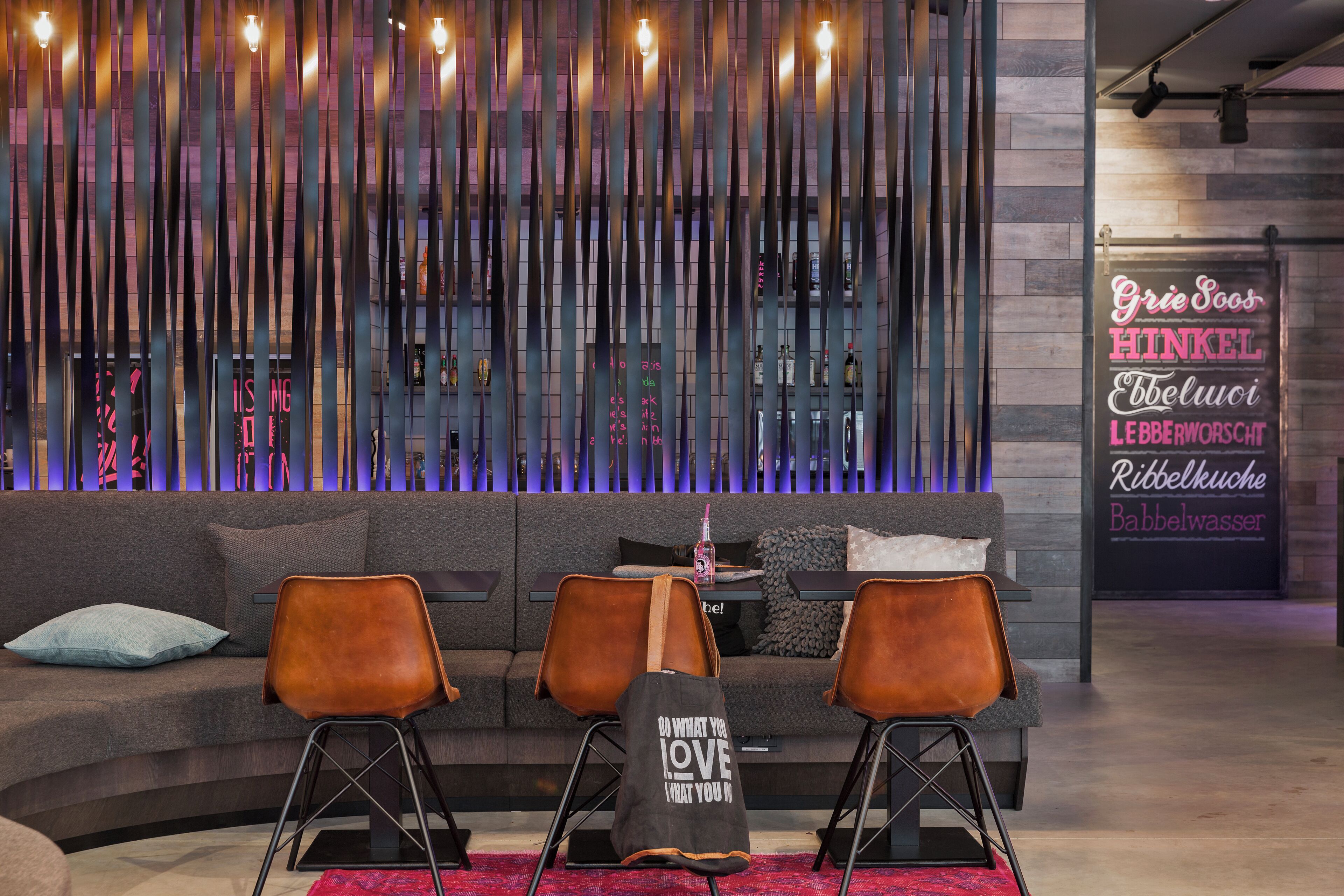 A modern interior with a sofa, two chairs, a decorative wall, and a sign with text.