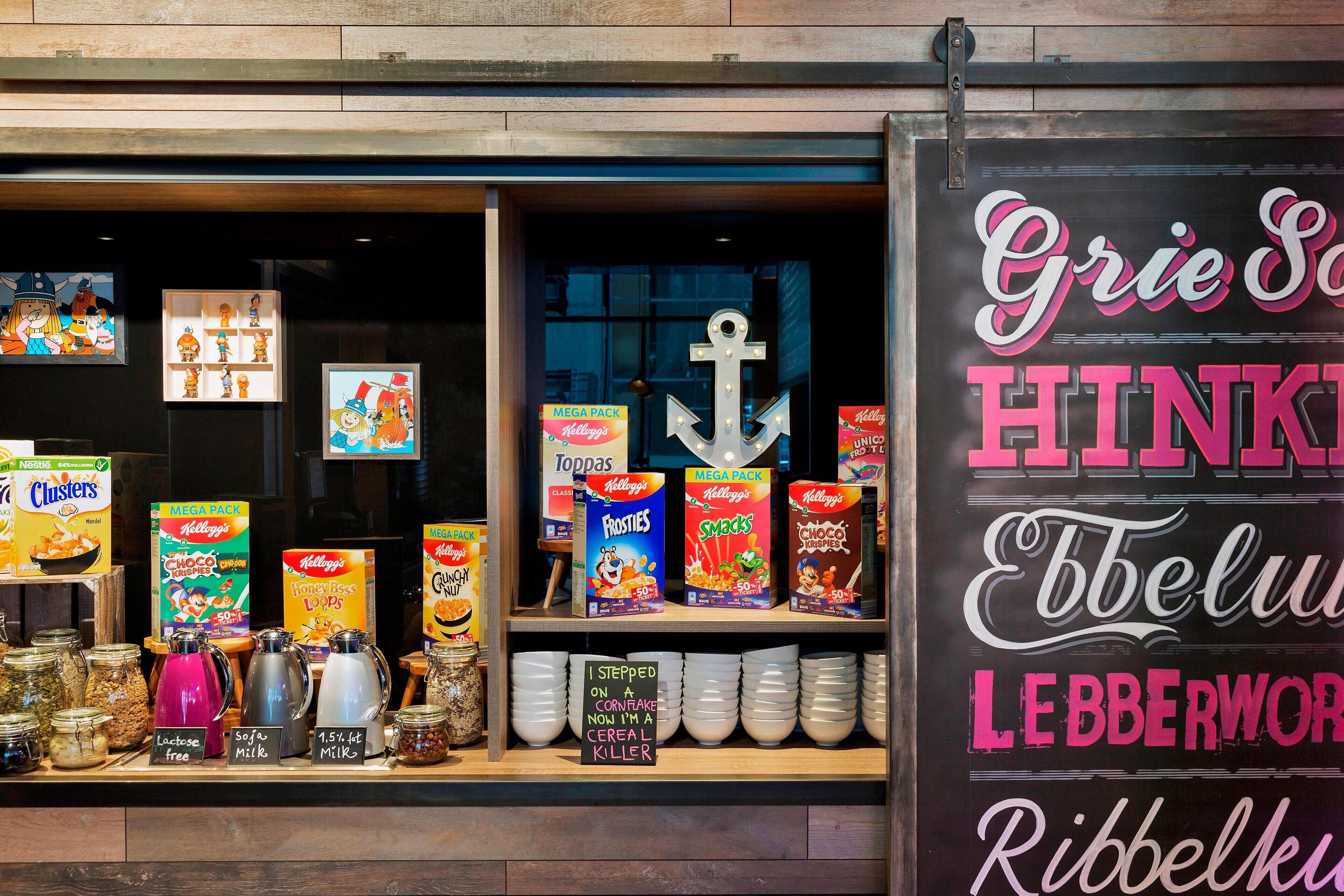 Exhibició de cereals amb diverses marques i sabors, incloent un cartell que diu 'He trepitjat un floc de blat de moro, ara sóc un assassí de cereals'.