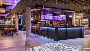 Un área de bar moderna con mostrador, taburetes y un letrero de neón.