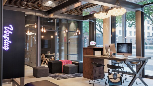 Un espacio de trabajo moderno con barra, asientos y un amplio ventanal con vistas a la ciudad.