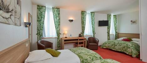 Ein Hotelzimmer mit zwei Betten, einem Schreibtisch, einem Stuhl und einem Fernseher.