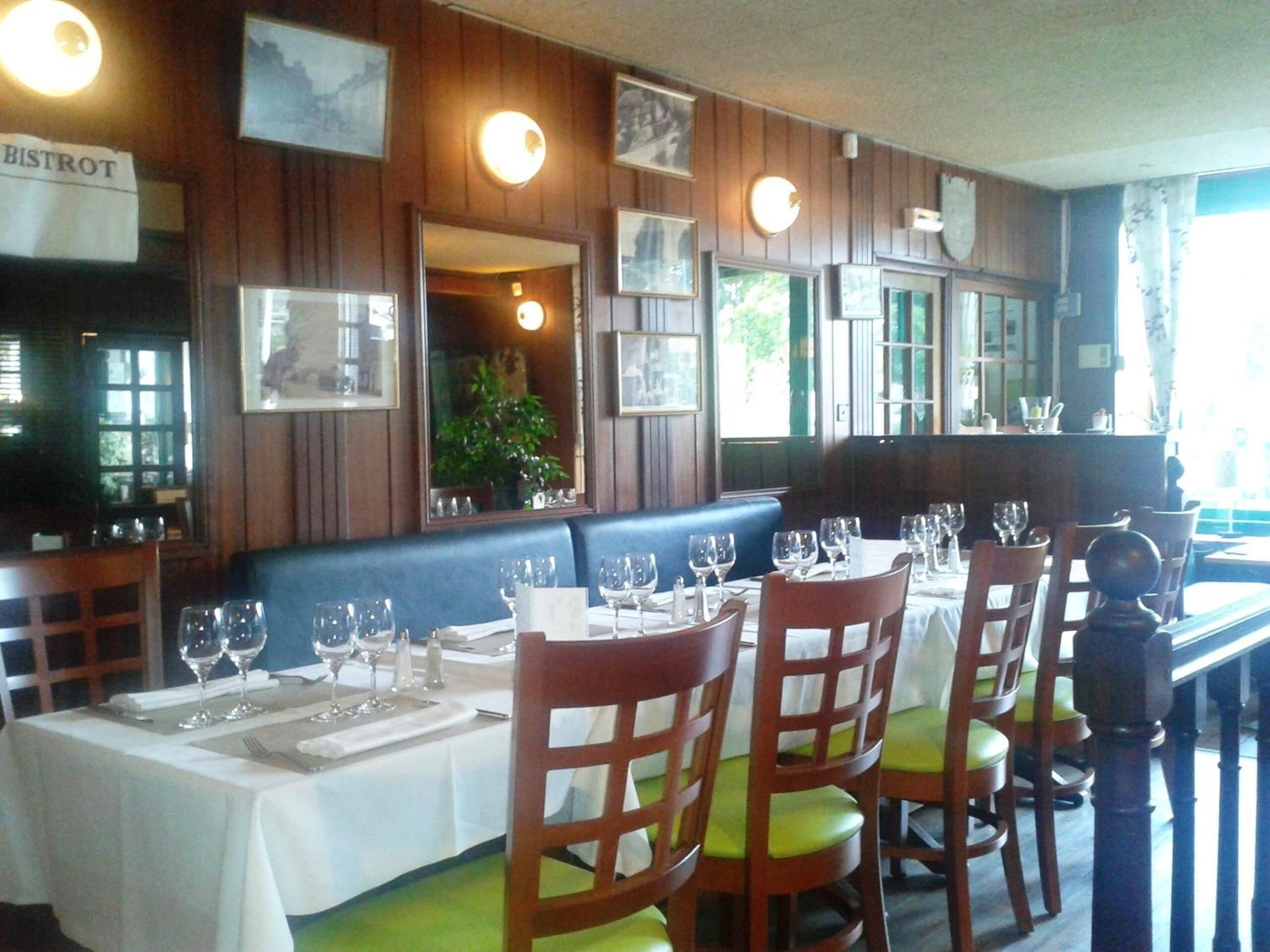 A restaurant interior with wooden paneling, a blue booth, and tables set for dining.