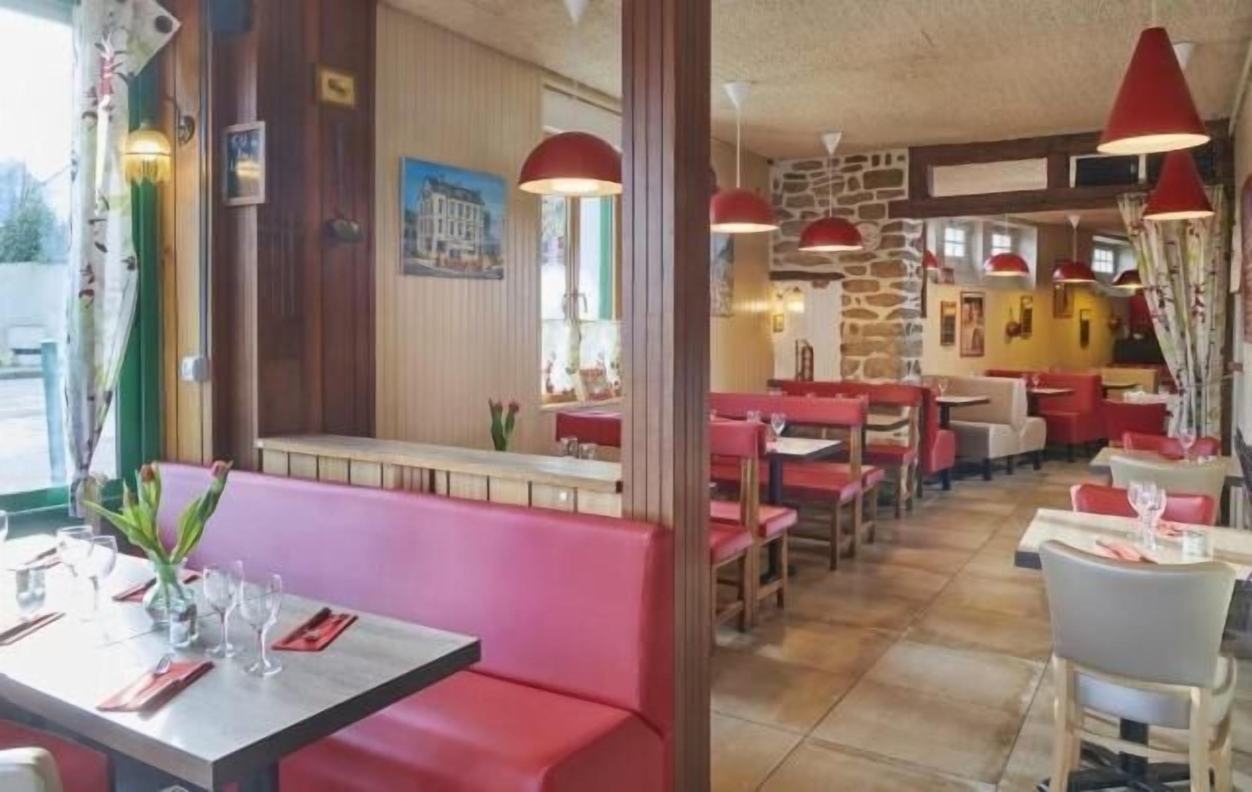 Interior de restaurante con cabinas y mesas, detalles de madera e iluminación colgante roja.