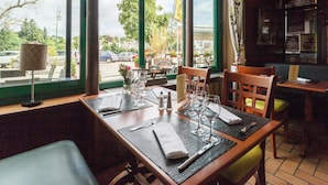 Un restaurante con vistas a la calle, amplios ventanales y una mesa dispuesta para comer.
