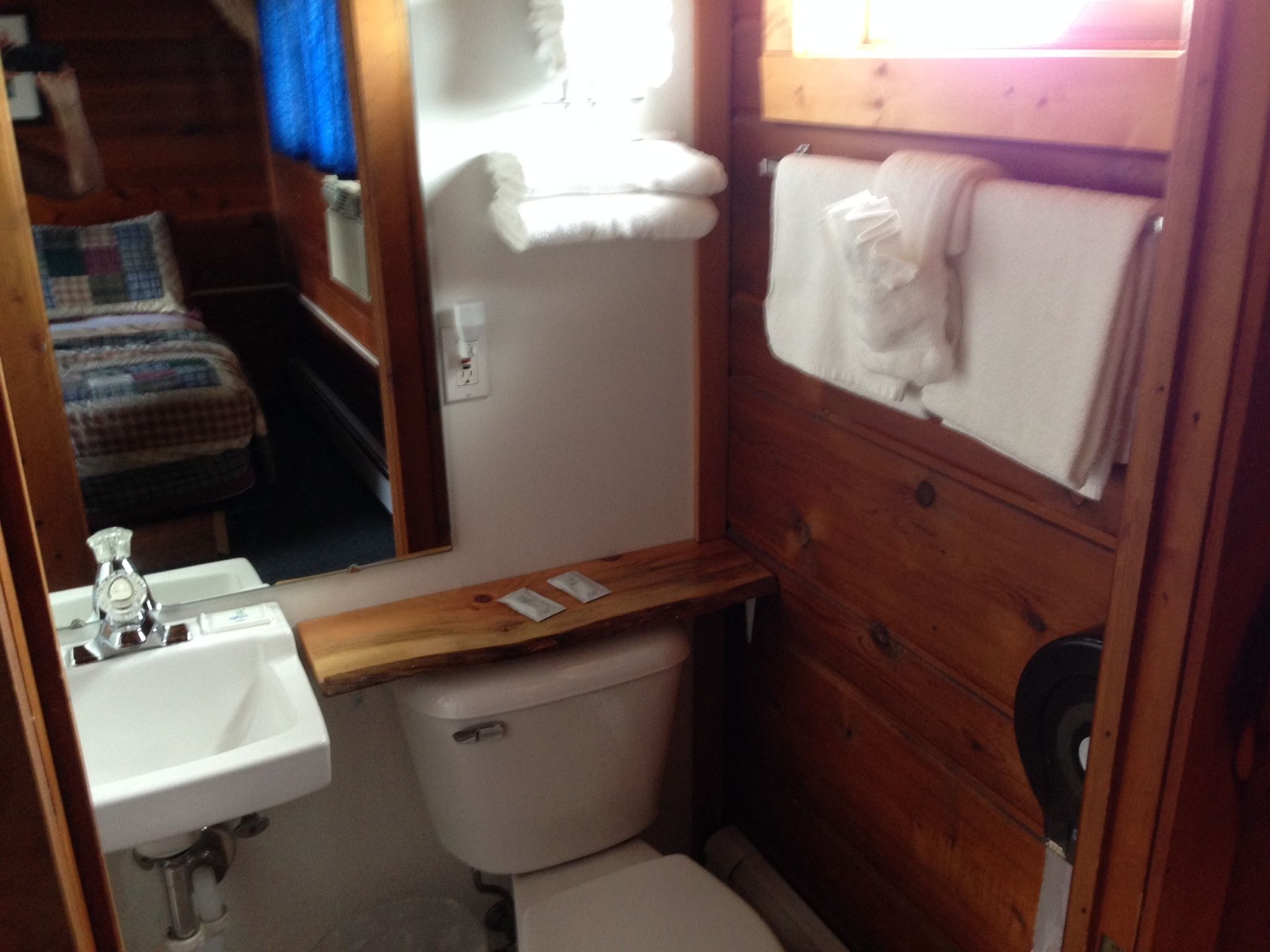Un baño pequeño con un mueble de tocador de madera, un lavamanos blanco y un inodoro.