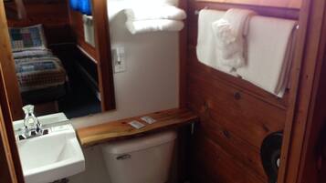 Un baño pequeño con un mueble de tocador de madera, un lavamanos blanco y un inodoro.