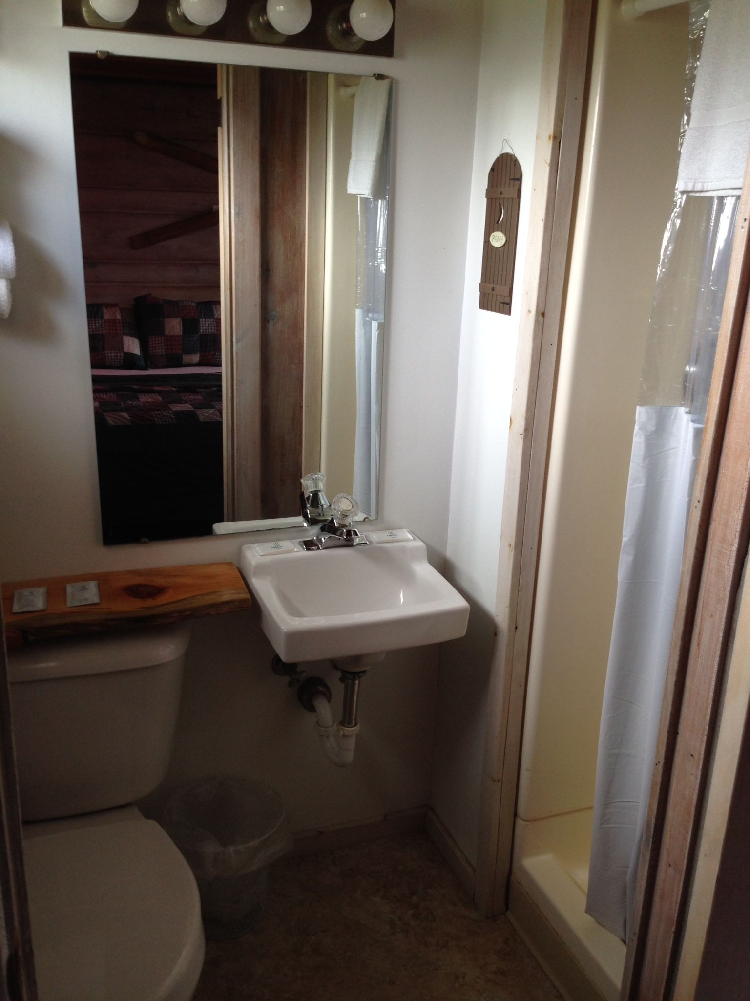 Une petite salle de bain avec un lavabo blanc, un miroir et des toilettes.
