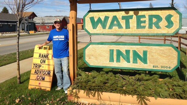 A wooden sign for Waters Inn with a 'Rank on TripAdvisor.com' sign beside it.