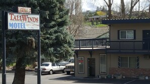 A motel named Tall Winds with a signboard, a building with a balcony, and parked cars. - Tall Winds Motel (Moro)