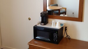 Une chambre d’hôtel avec une commode en bois, une machine à café et un miroir orné d’un cadre avec une photo.