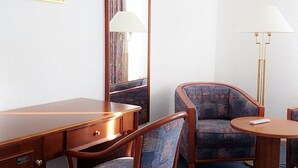 A hotel room with a wooden desk, a chair, a round table, and a large mirror. - Fichtelberghütte (Oberwiesenthal)