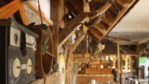 A rustic interior with wooden beams, a jukebox, and wooden tables. - Fichtelberghütte (Oberwiesenthal)