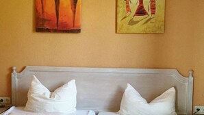 A hotel room with a double bed, white bedding, and two pillows. There are two paintings on the wall above the bed. - Fichtelberghütte (Oberwiesenthal)